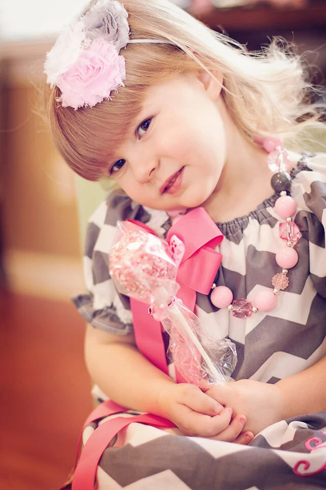 Toddler girl in a pink flower headband at a Valentine's party