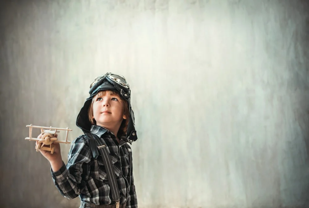 Boy in an aviator hat playing with a toy airplane