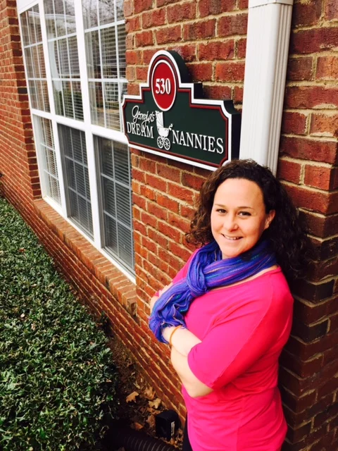 Jessica, placement coordinator, by the Georgia's Dream Nannies office sign