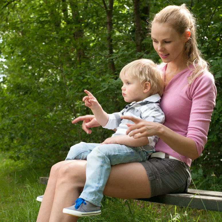 Woman holding a toddler on a park bench