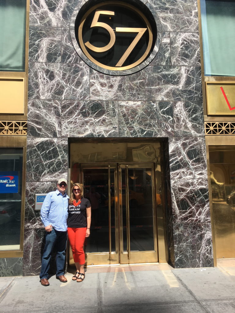 Man and woman standing outside a building entrance marked 57