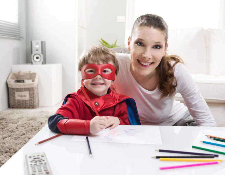 Mother and boy in a superhero mask drawing together