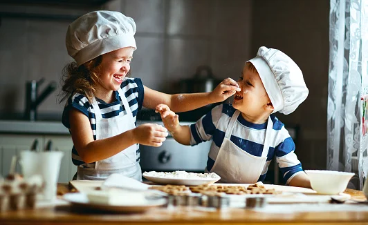 Two children in chef hats baking