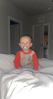Baby with a pacifier lying on a bed