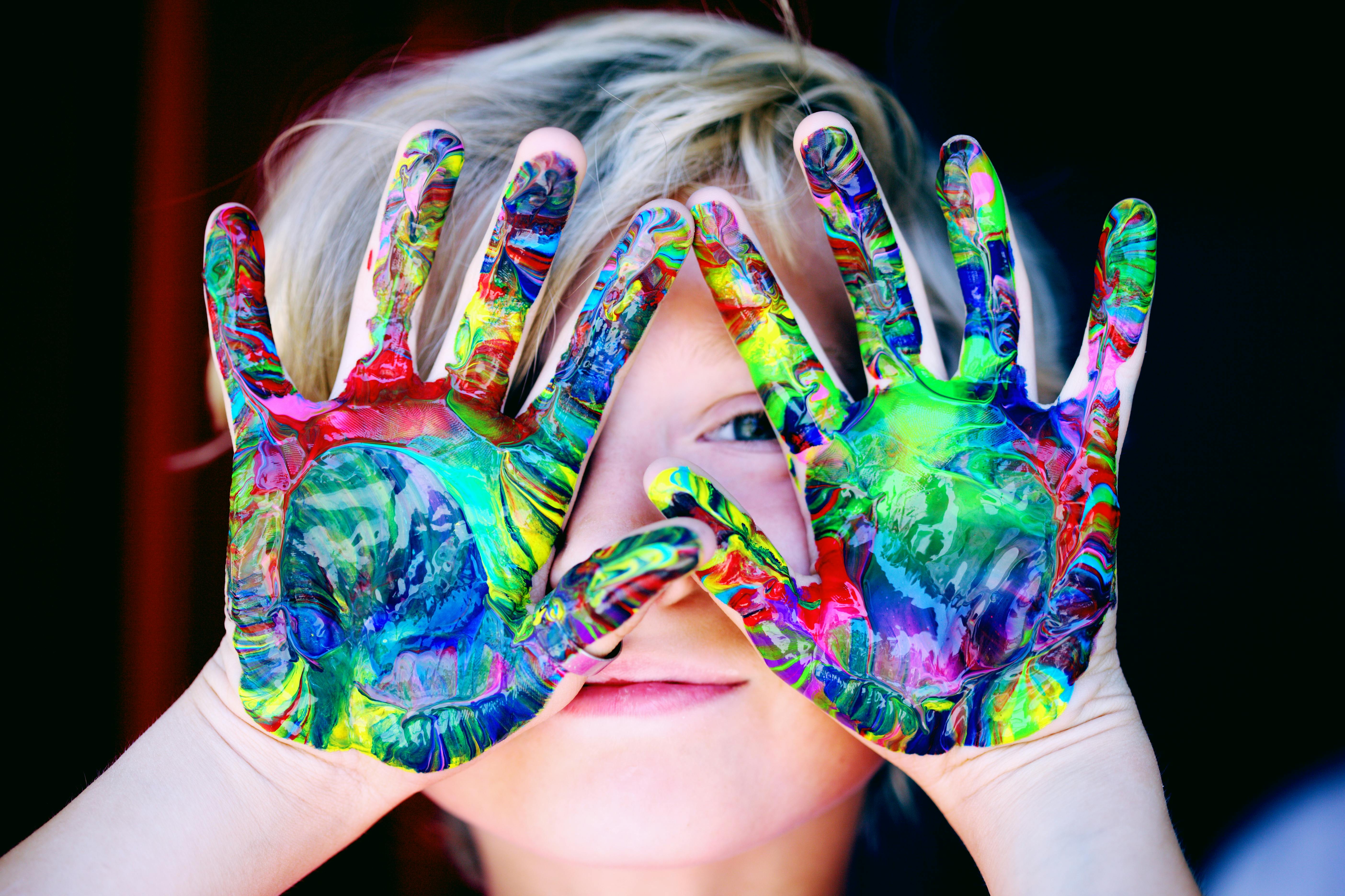 Child with paint on their hands enjoying creative play with a weekend nanny in Charlotte.
