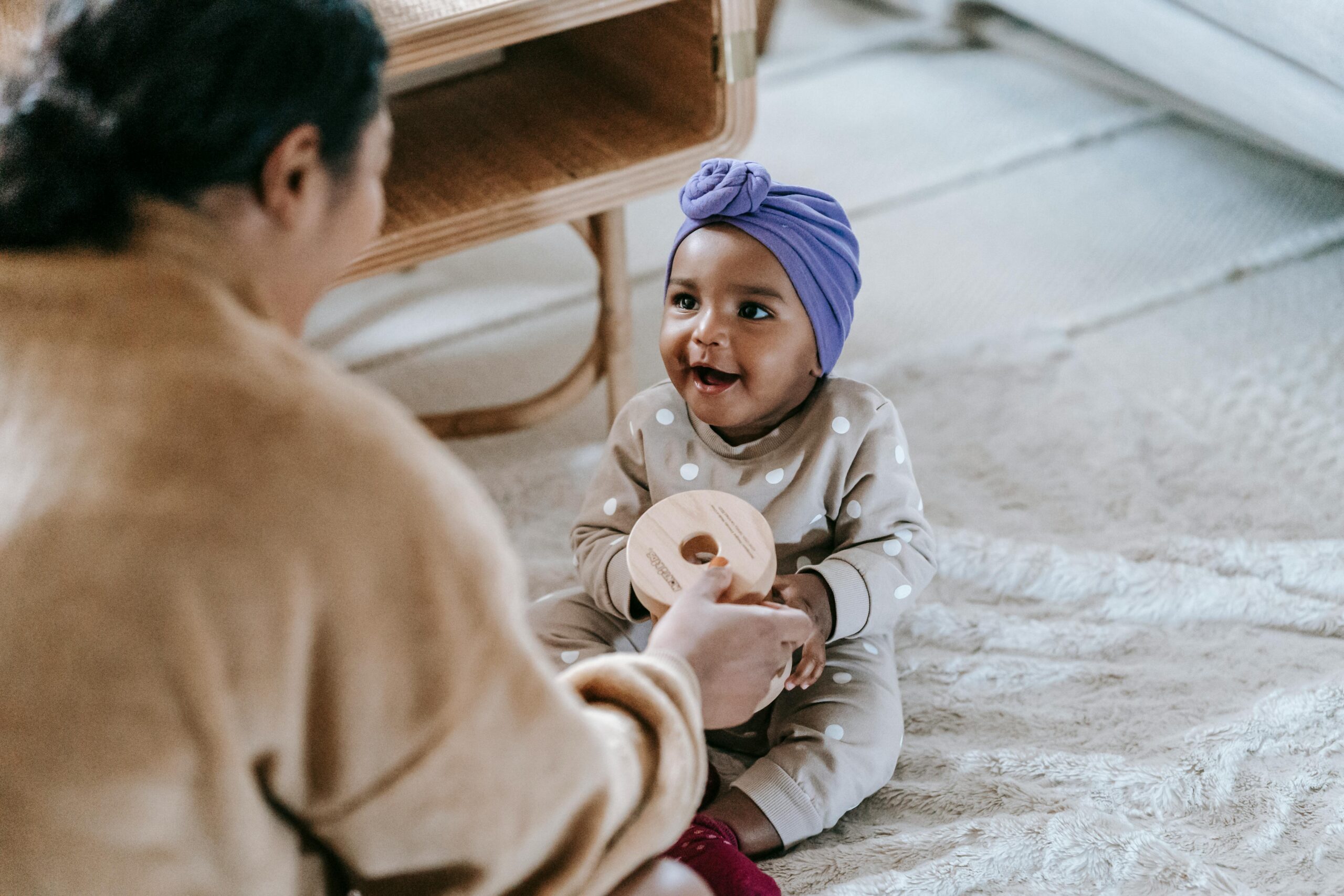 Caregiver playing with a smiling baby in a headwrap