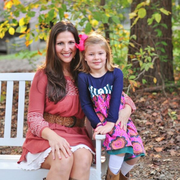 Woman and young girl smiling on a white garden bench in autumn - Dream Nannies Household Staffing